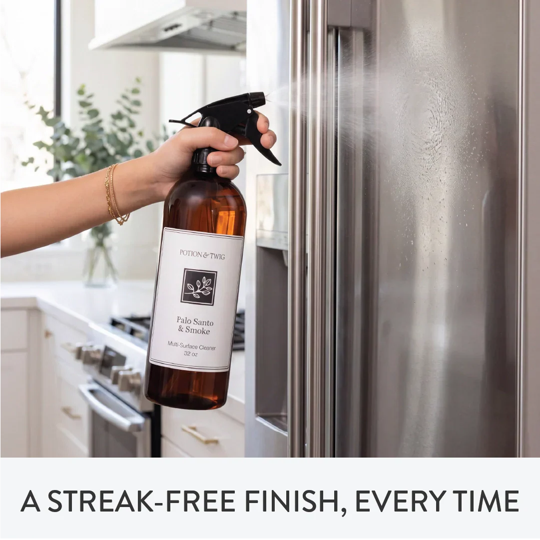Person using a cleaning spray bottle branded "Potion & Twig" on a refrigerator with text 'A Streak-Free Finish, Every Time'.