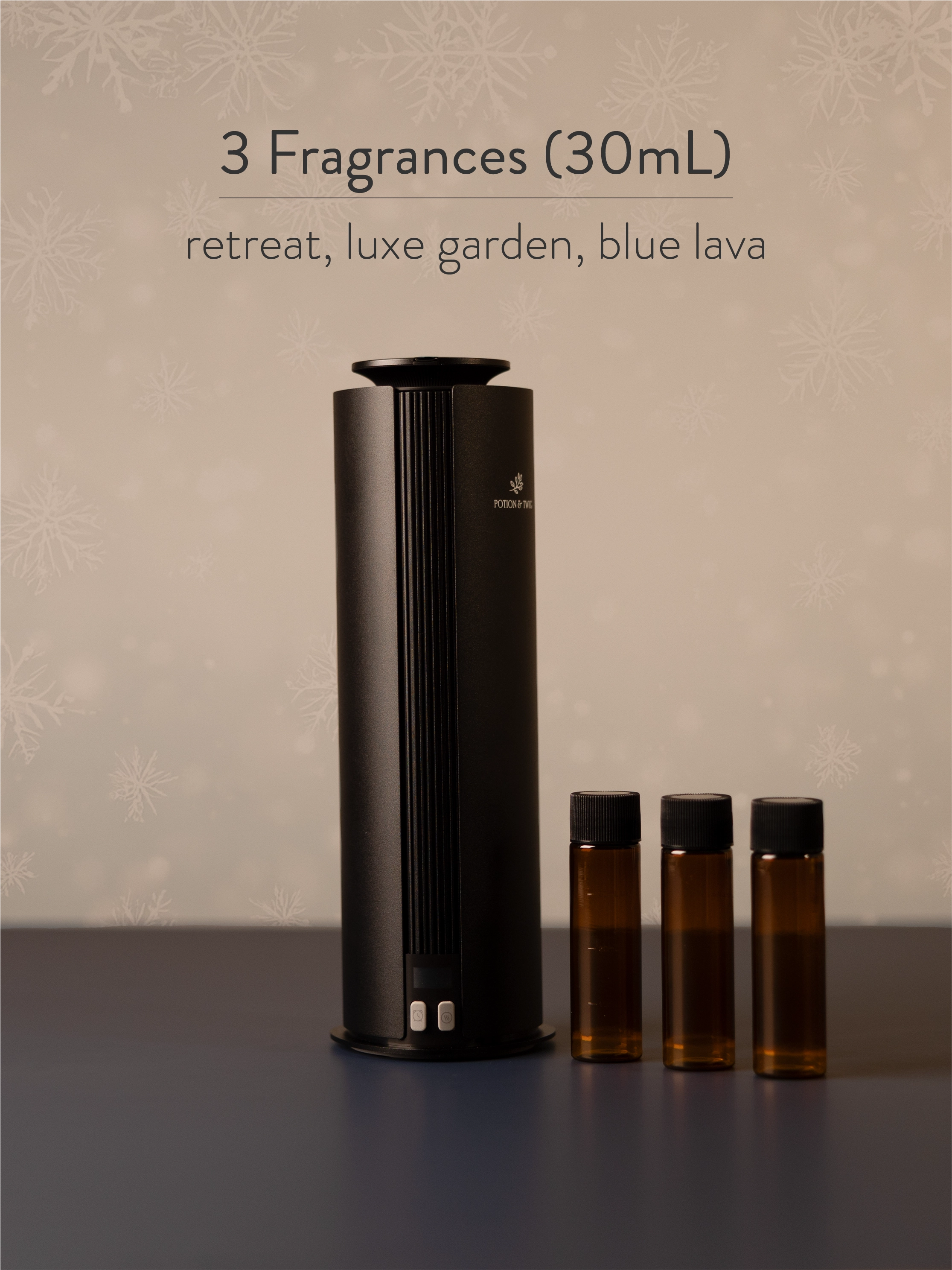 Black diffuser with three small brown bottles labeled 'retreat', 'luxe garden', and 'blue lava' on a neutral background.