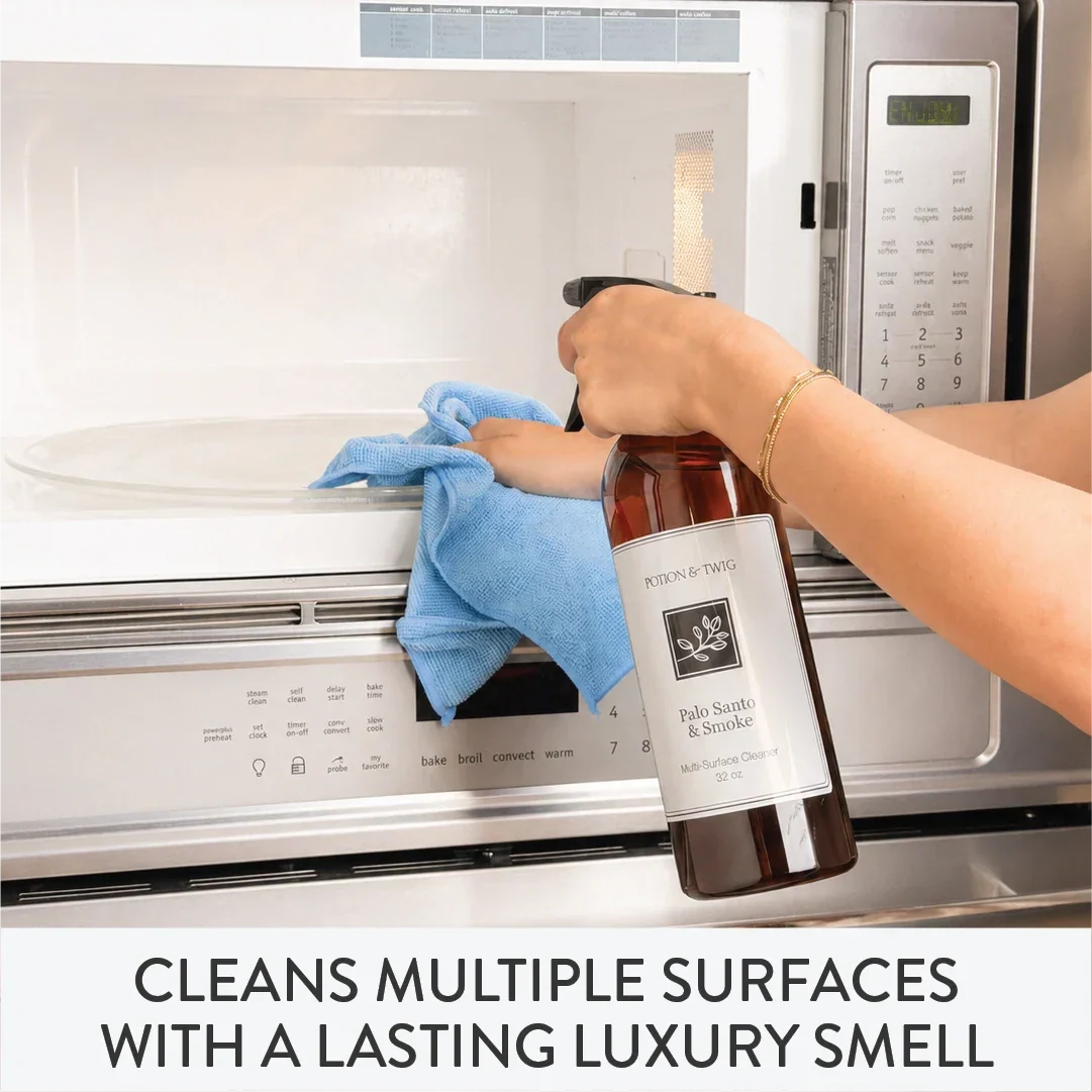 Person cleaning a microwave with a bottle of cleaning solution branded "Potion & Twig"