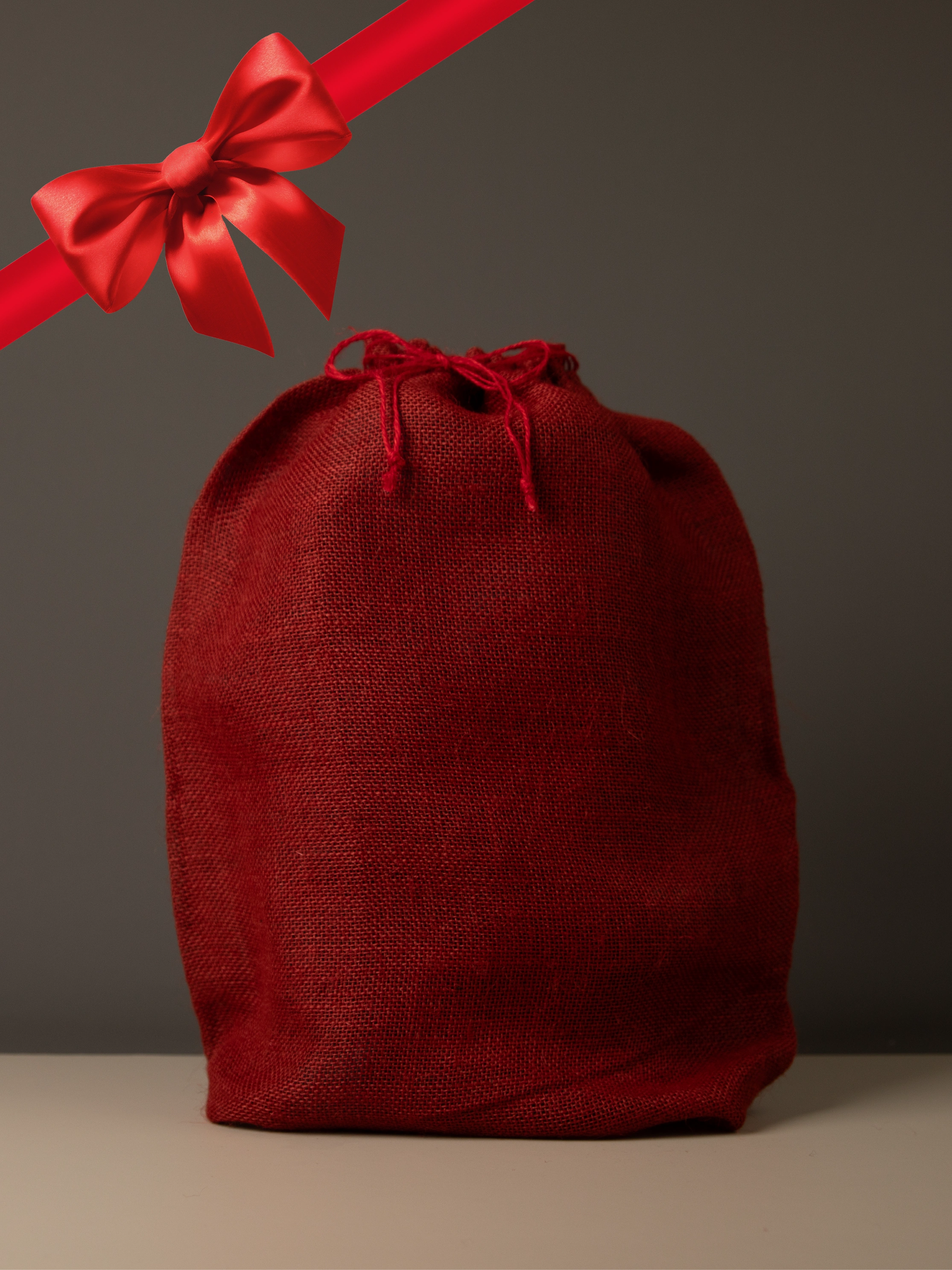 Red drawstring gift bag with a red ribbon on a gray background
