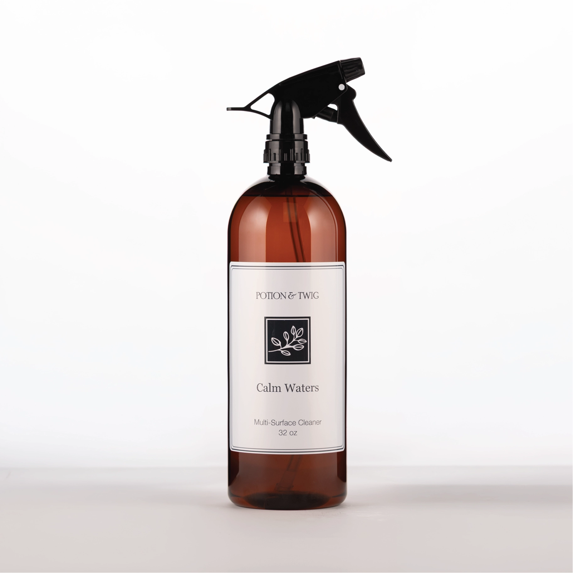 Brown spray bottle with 'Potion & Twig' brand label. On a white background. Labeled Calm Waters Multi-Surface Cleaner