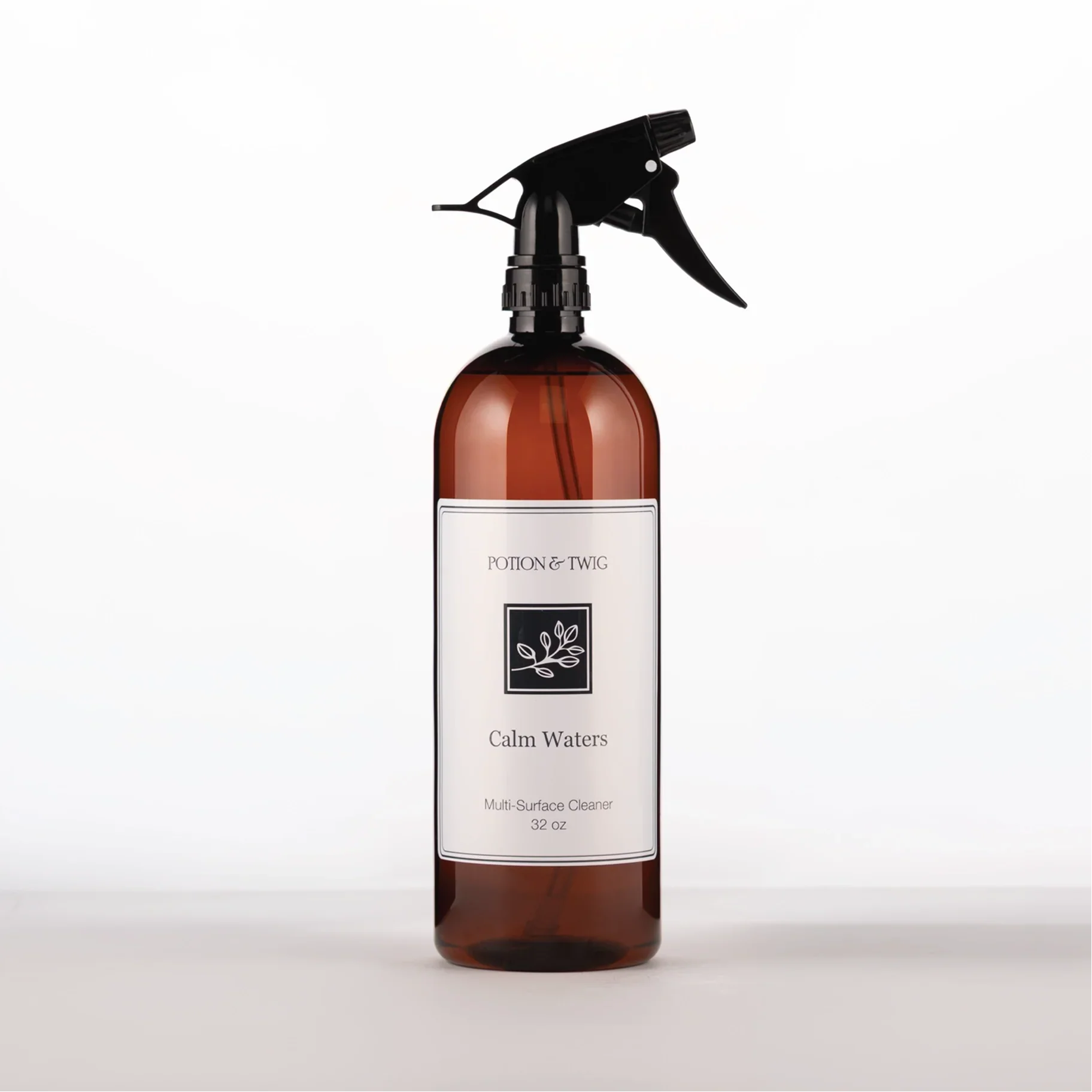 Brown spray bottle with 'Potion & Twig' brand label. On a white background. Labeled Calm Waters Multi-Surface Cleaner