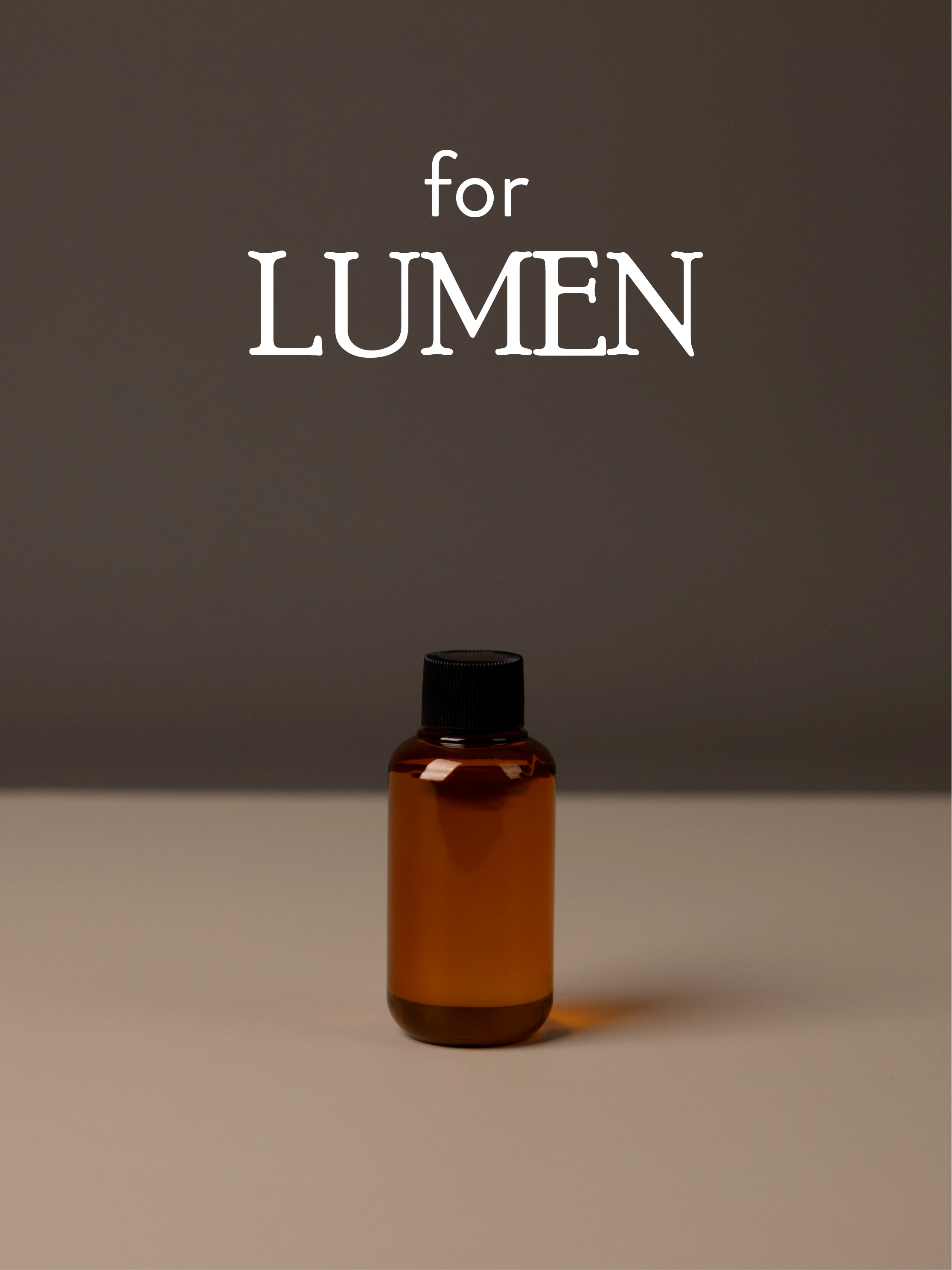 Amber diffuser oil bottle with black cap on a gray background, featuring 'for LUMEN' text.