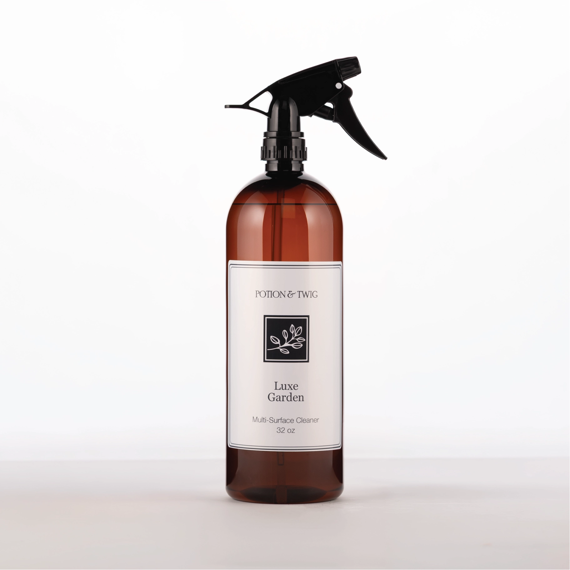 Brown spray bottle with 'Potion & Twig' brand label. On a white background. Labeled Luxe Garden Multi-Surface Cleaner