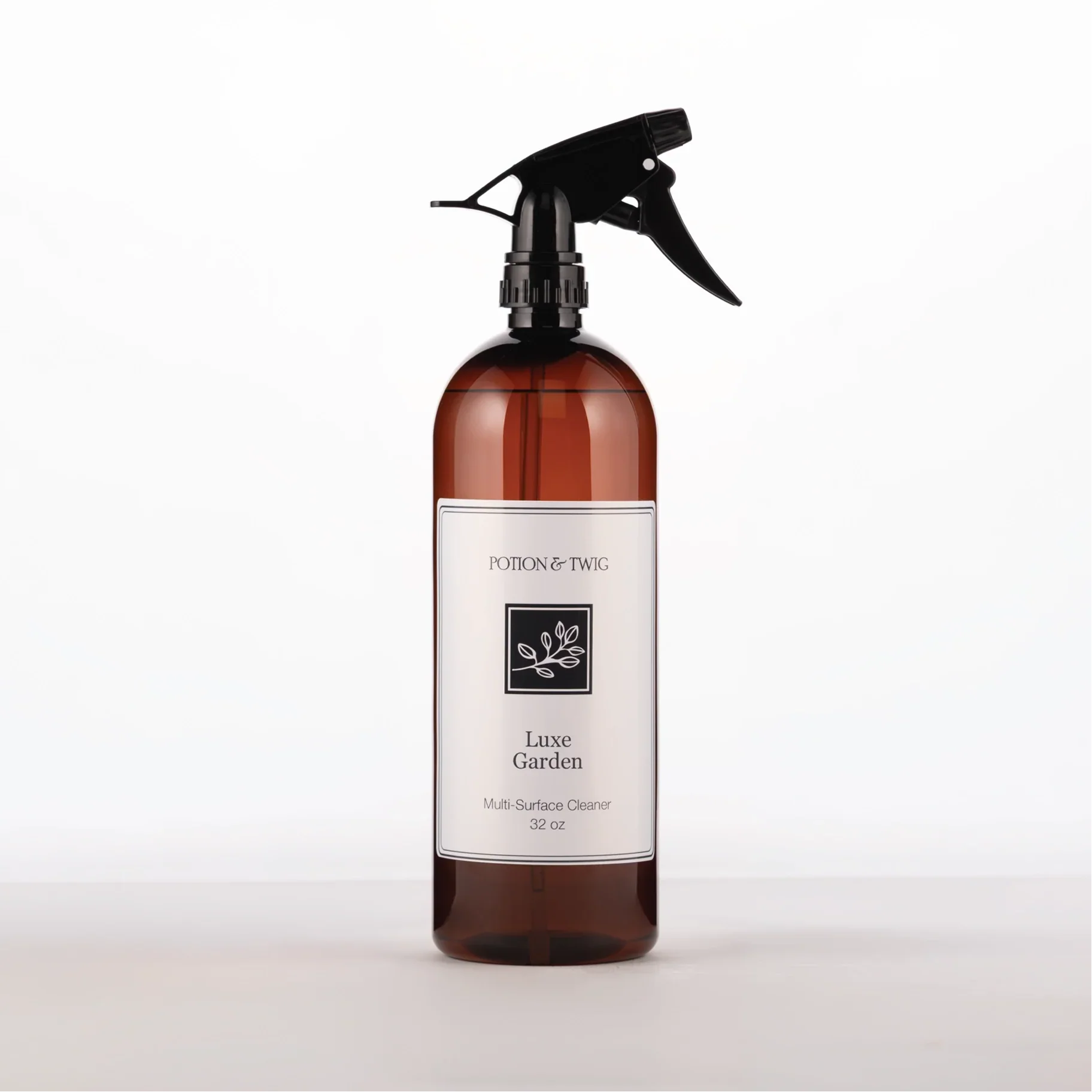 Brown spray bottle with 'Potion & Twig' brand label. On a white background. Labeled Luxe Garden Multi-Surface Cleaner