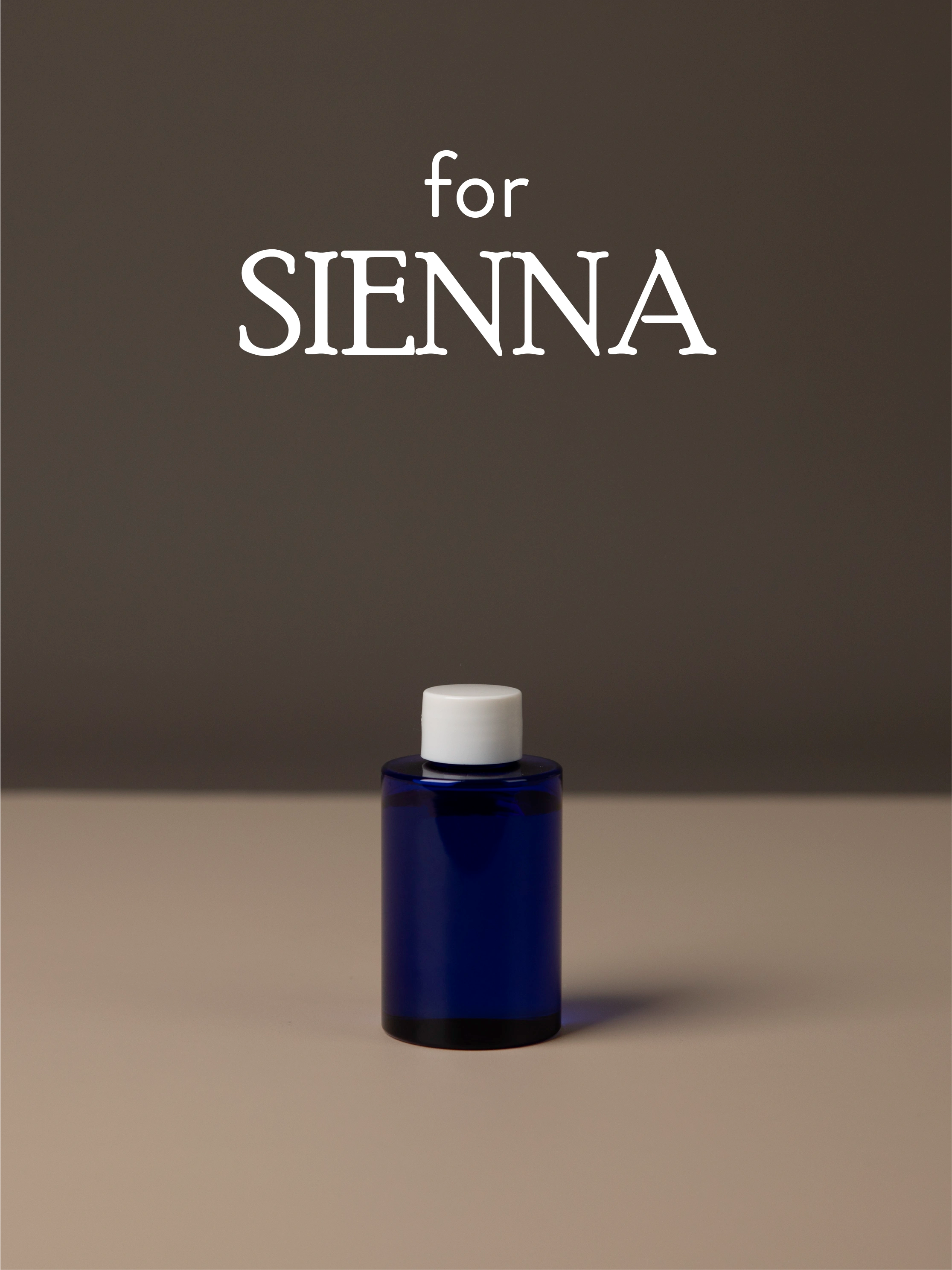 Blue diffuser oil bottle with white cap on a brown background, featuring the text 'for SIENNA'.