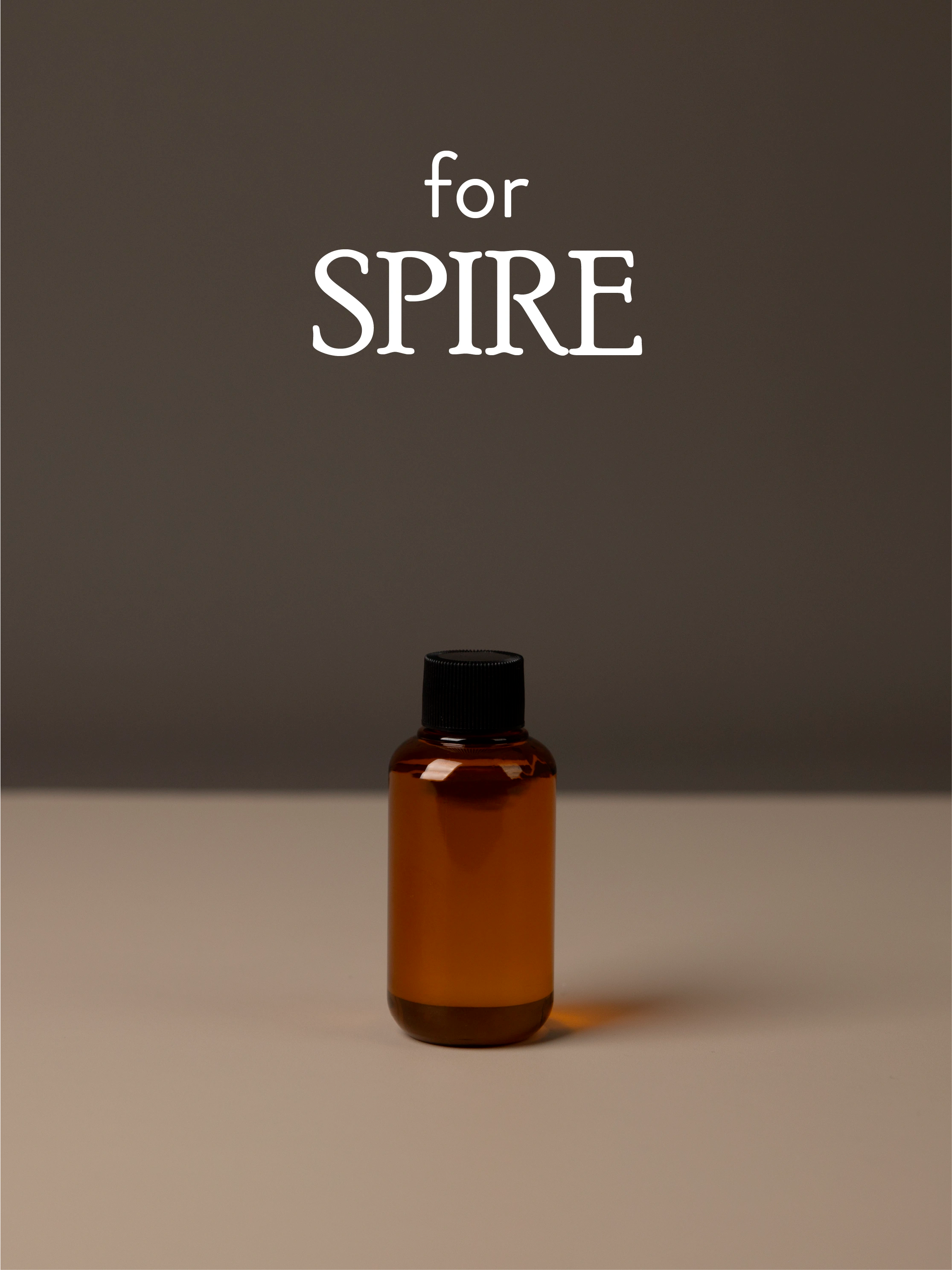 Amber diffuser oil bottle with black cap on a gray background, featuring the text 'for SPIRE'.