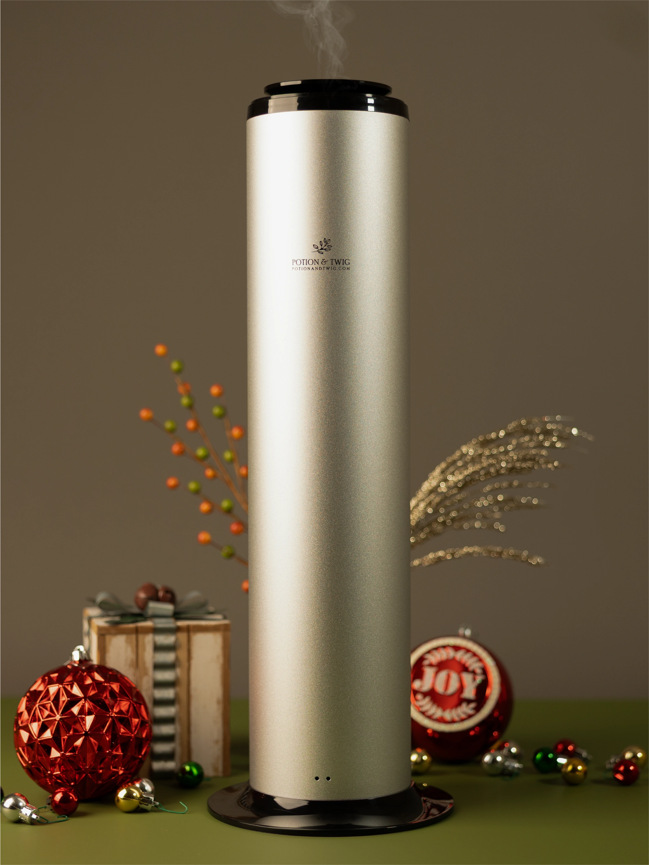 Tall silver Terra Fragrance diffuser with holiday decorations around it.