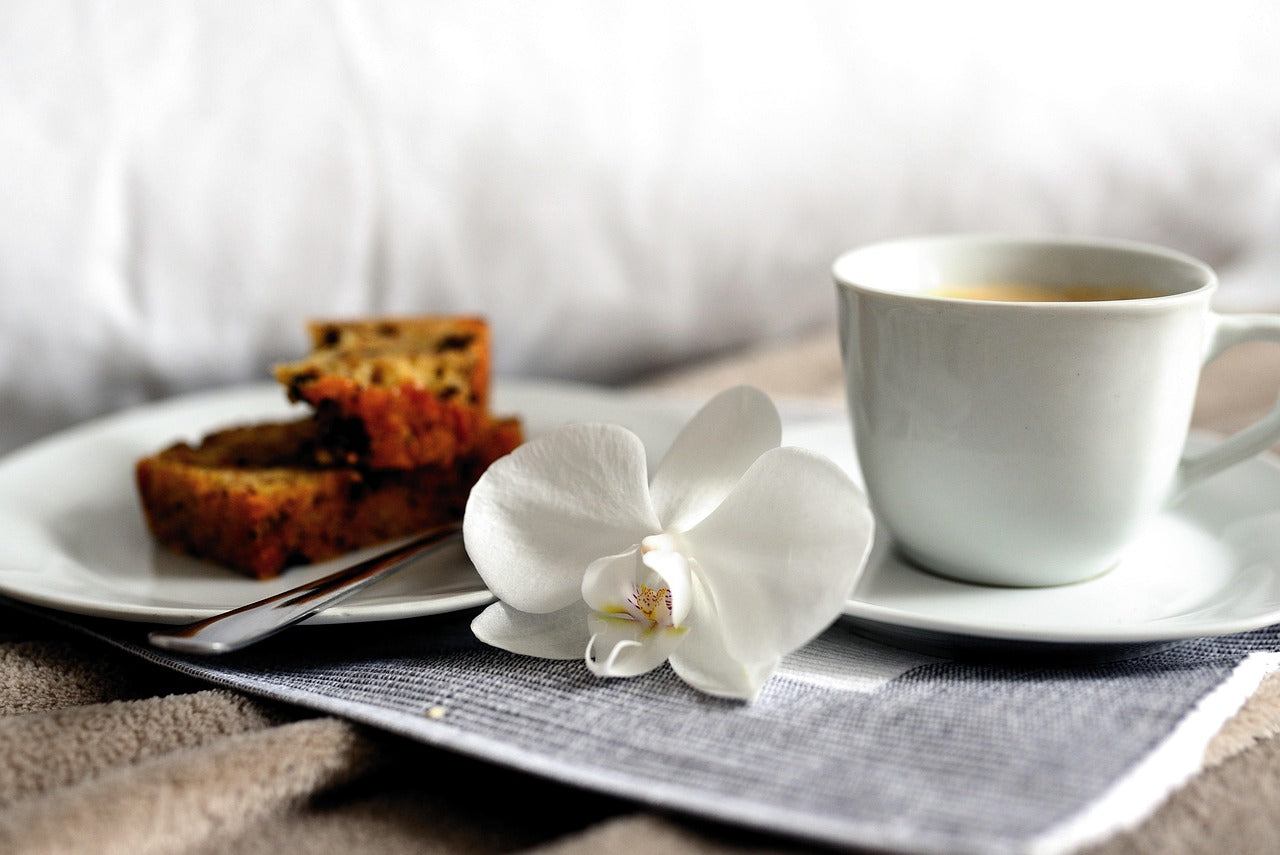 Spice cake, cup of tea, and a flower on a table with a light background