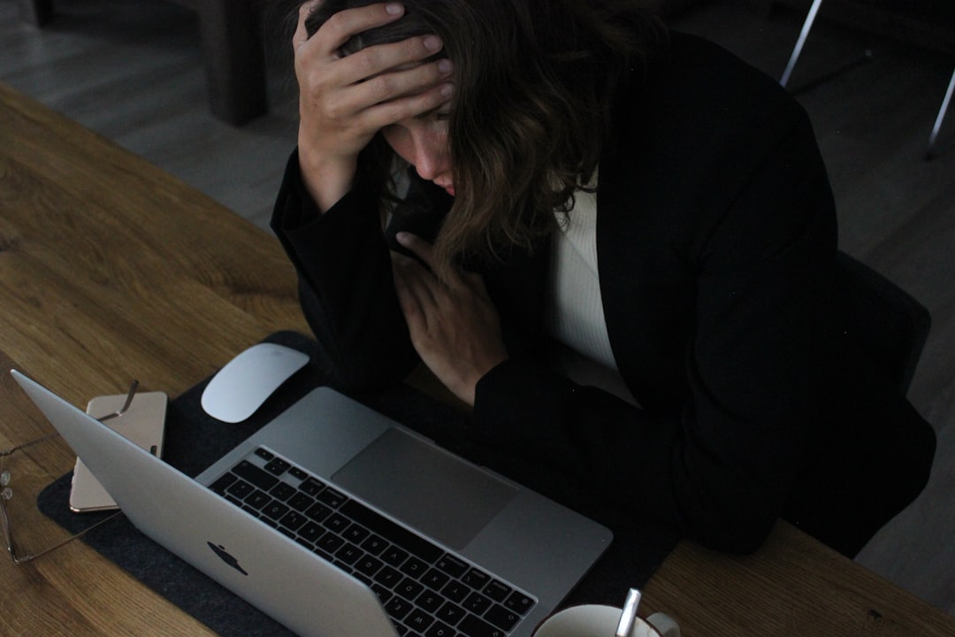 Stressed woman with her head in her hands over a laptop.