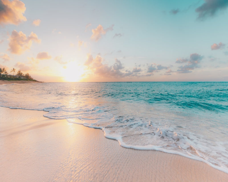 Beach scene with waves crashing onto the shore at sunset.