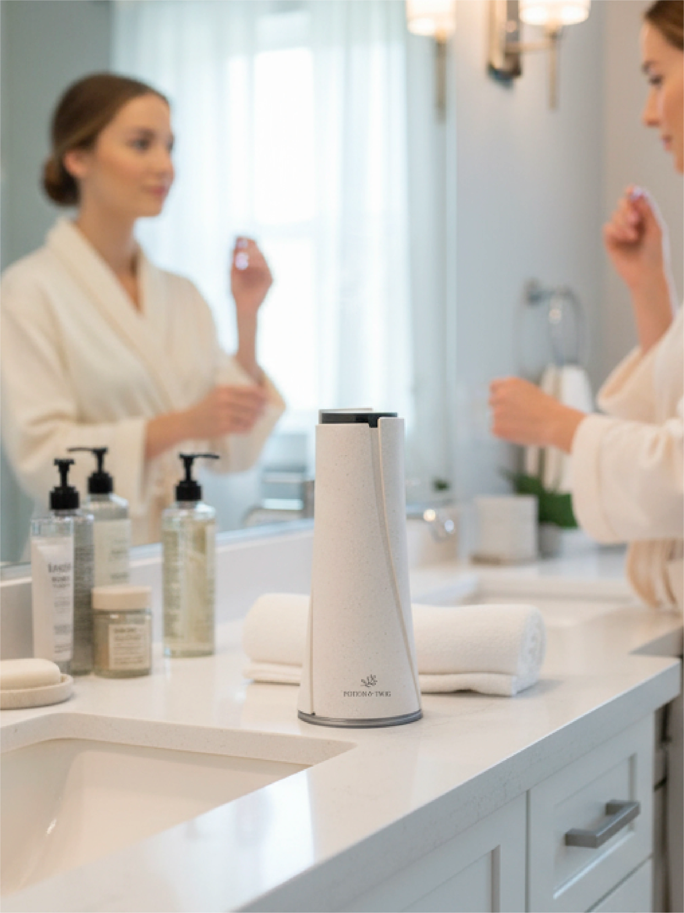 Woman applying lotion in front of a mirror with a white Lumen wireless scent diffuser on the counter.