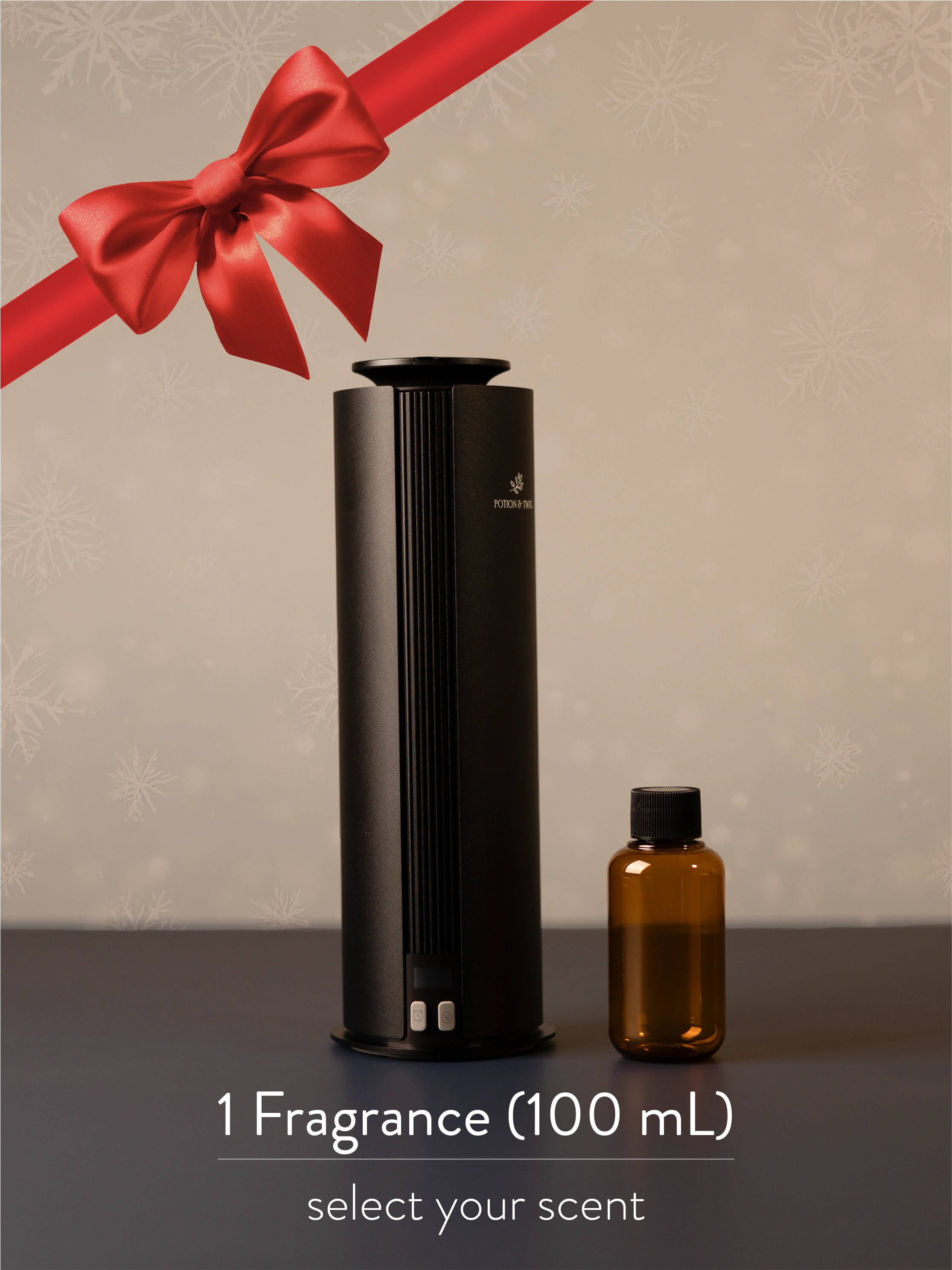Black fragrance diffuser with a red bow and an amber fragrance oil bottle on a neutral background