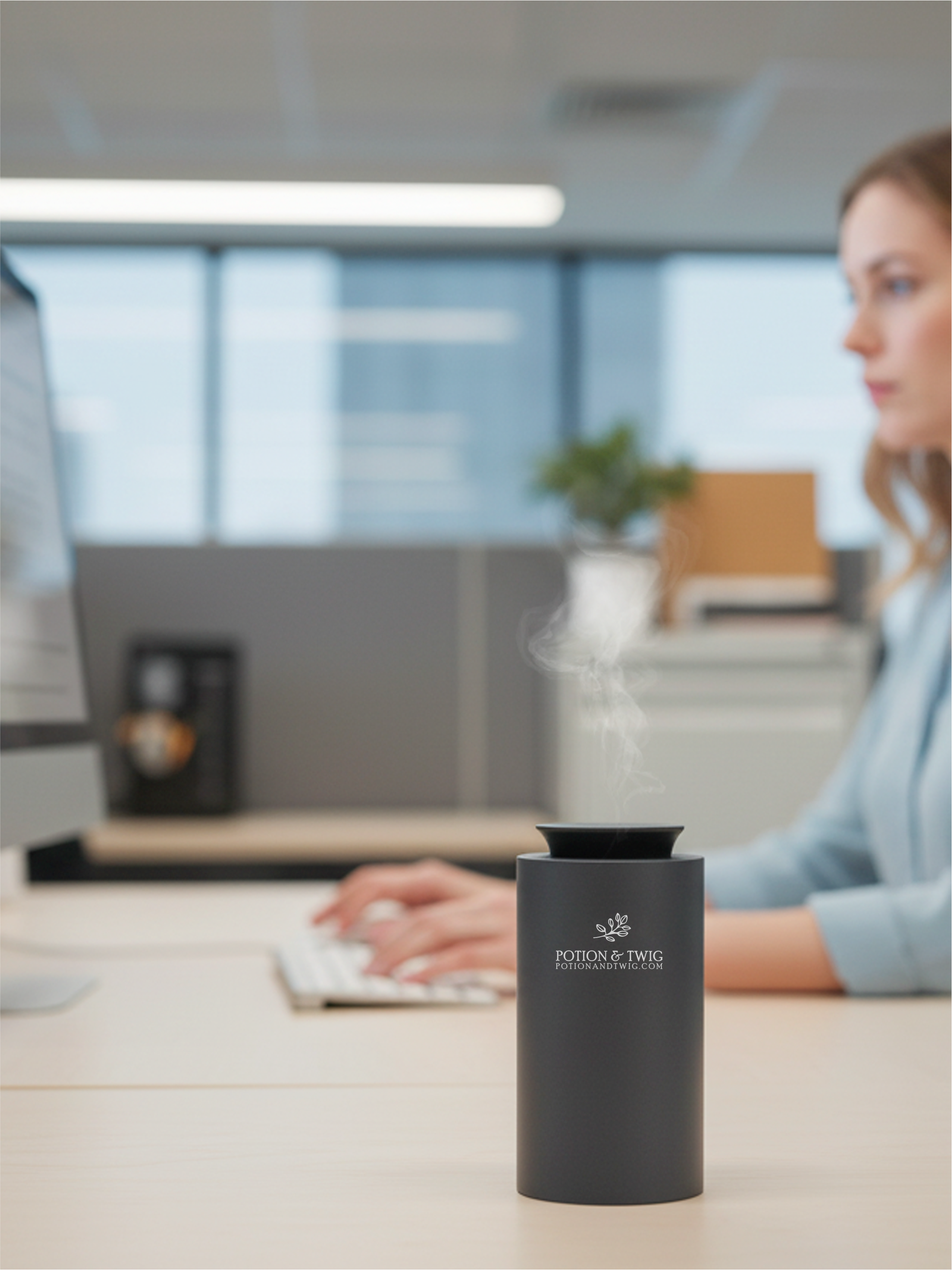 Person using a computer with a black Companion scent diffuser on a desk in an office setting