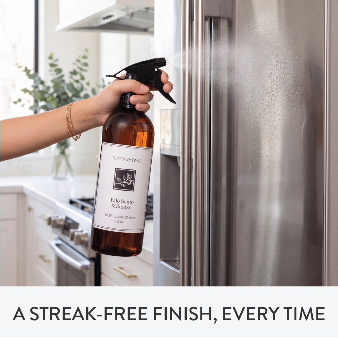 Person using a cleaning spray bottle branded "Potion & Twig" on a refrigerator with text 'A Streak-Free Finish, Every Time'.
