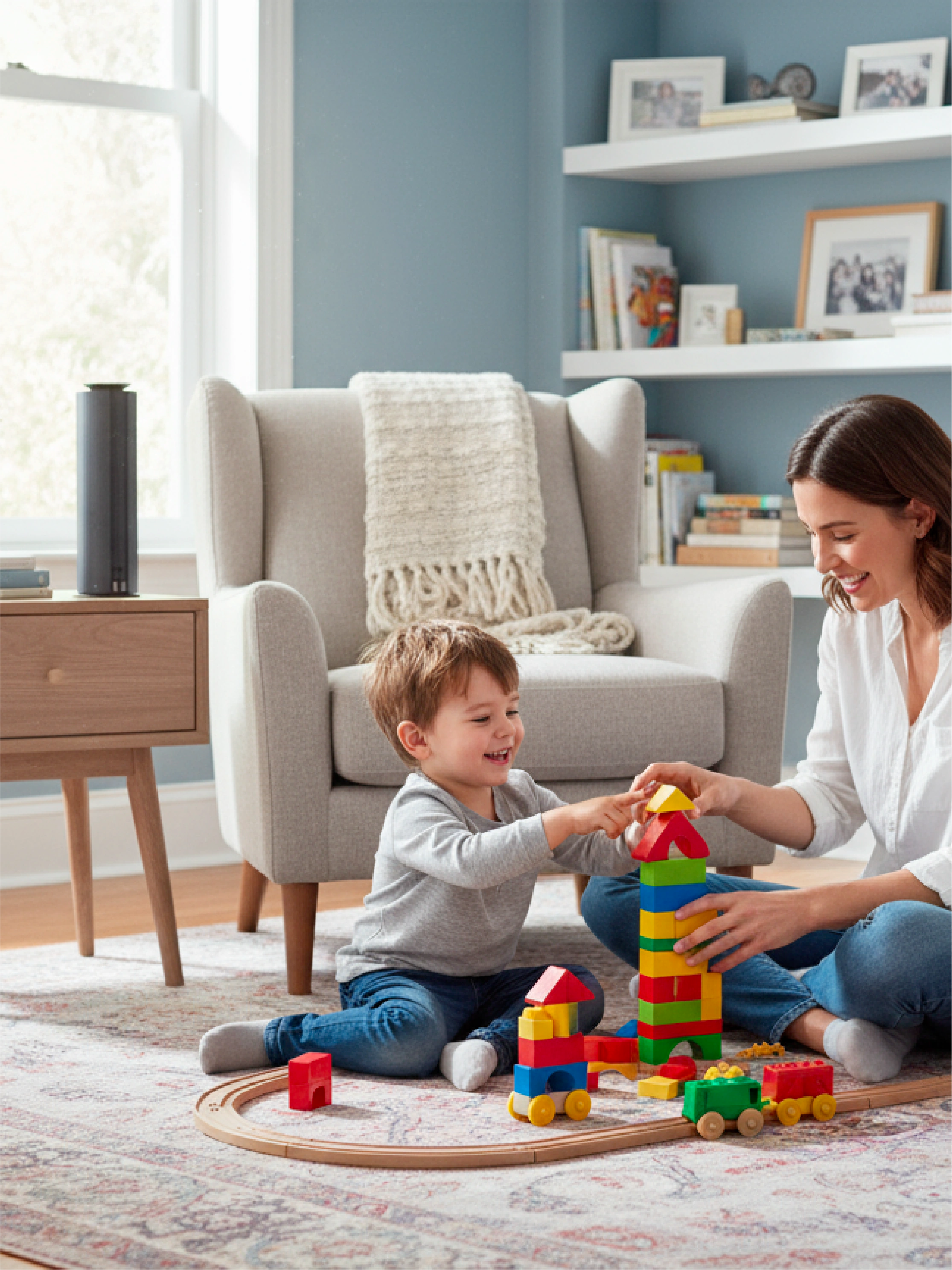 Woman and child playing with colorful building blocks in a living room.With a Spire wireless scent diffuser on the table.