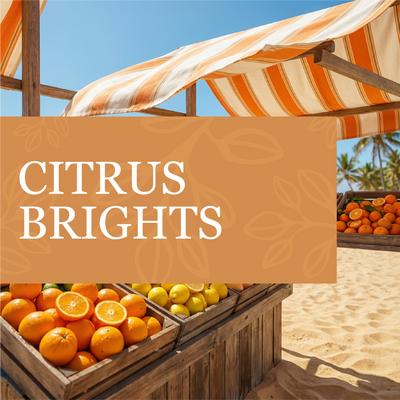 Oranges and lemons displayed under a striped umbrella with 'Citrus Brights' text on a beach.