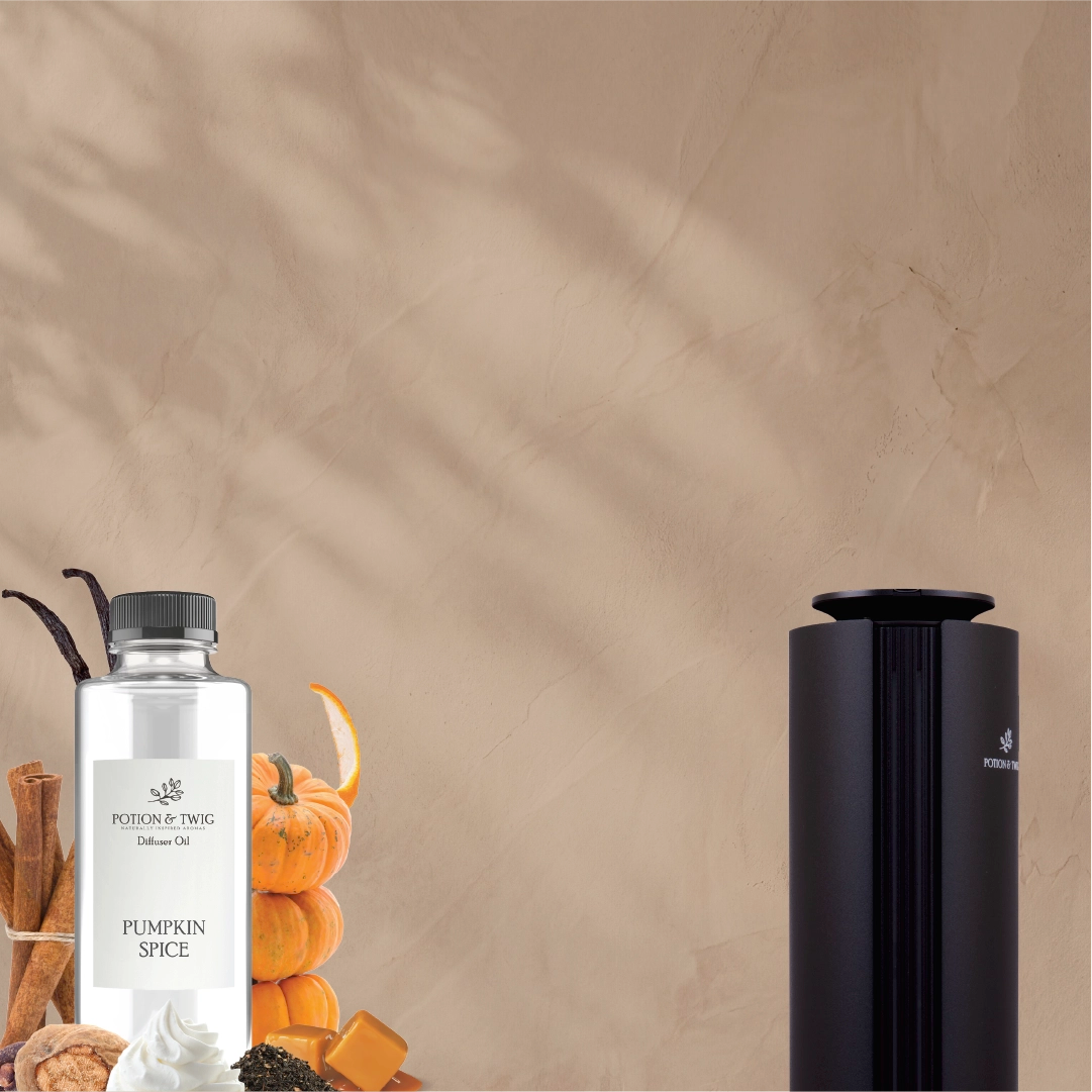 A bottle of Pumpkin Spice diffuser oil by Poudrerie Doug next to a black cylindrical diffuser, styled with autumn spices and pumpkins against a textured beige wall with leaf shadows.