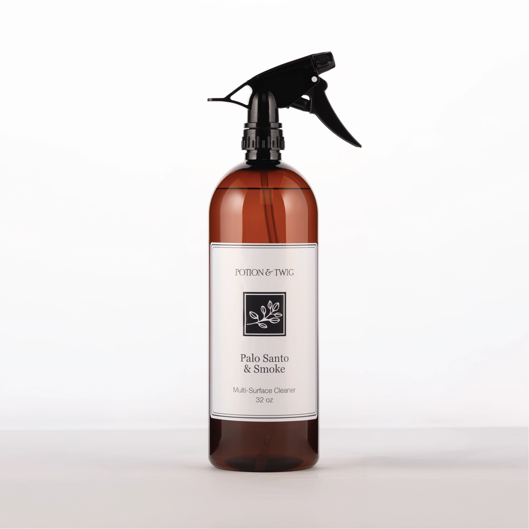 Brown spray bottle with 'Potion & Twig' brand label. On a white background. Labeled Palo Santo & Smoke Multi-Surface Cleaner