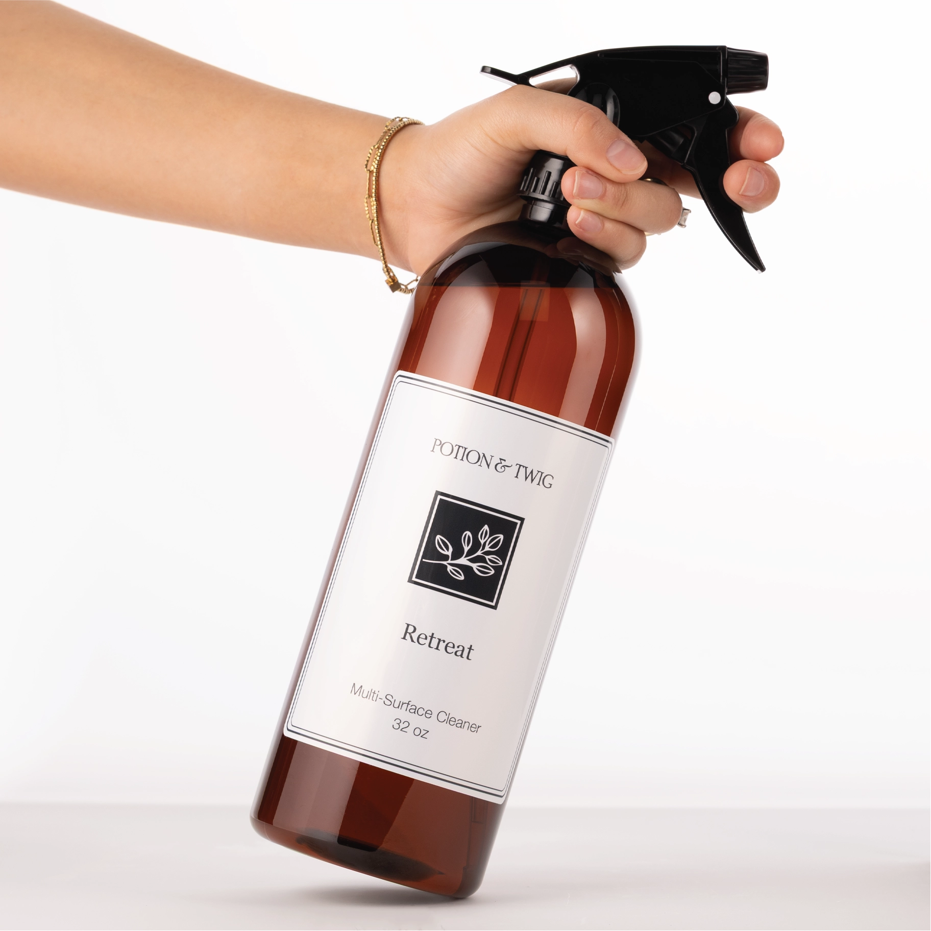 Hand holding a Potion & Twig 'Retreat' multi-surface cleaner bottle against a white background