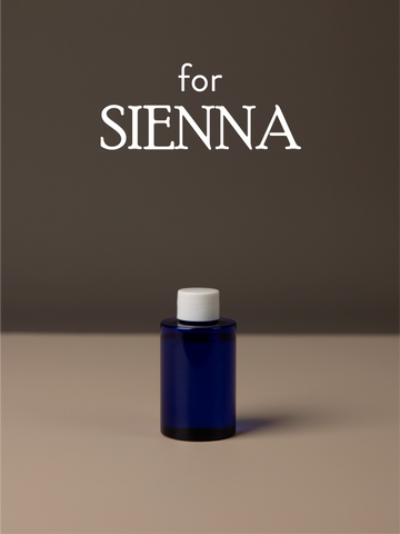 Blue diffuser oil bottle with white cap on a brown background, featuring the text 'for SIENNA'.