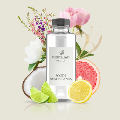 Bottle of Potion & Twig diffuser oil with tropical fruits and flowers on a light background. Label reads South Beach Sands