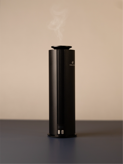 Black cylindrical scent diffuser on light neutral background