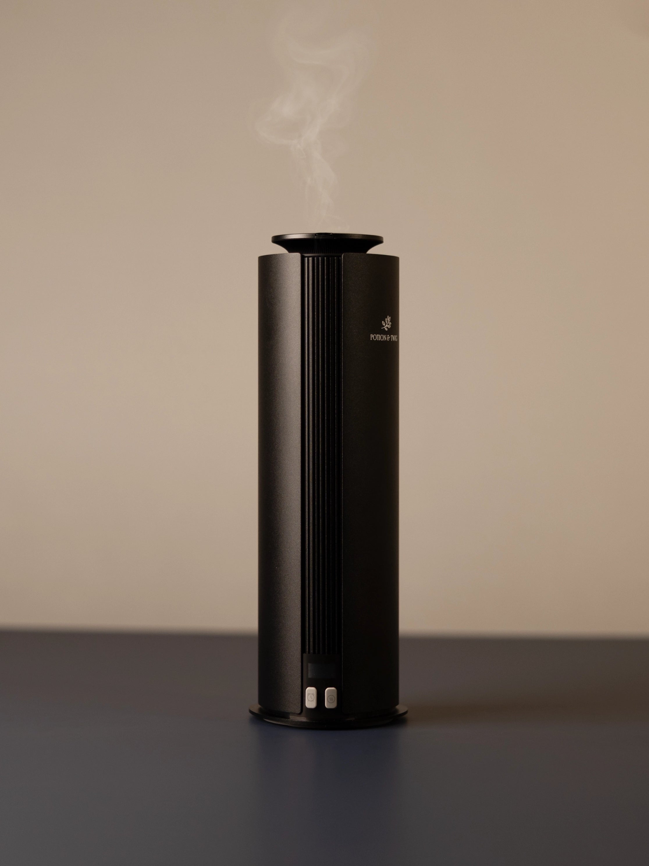 Black cylindrical scent diffuser on light neutral background